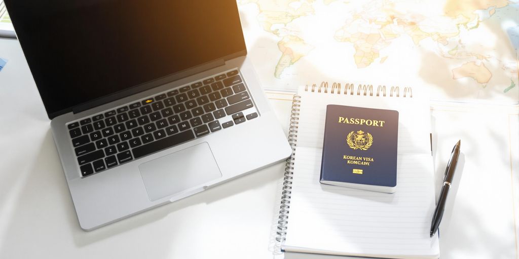 Desk with laptop, notebook, passport and pen