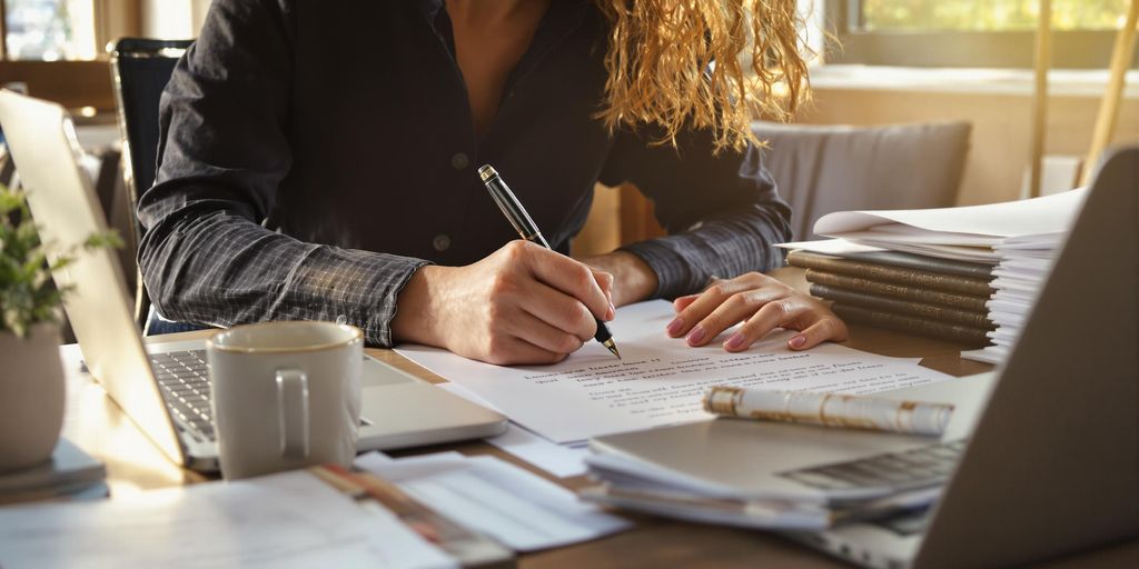 Person writing cover letter at tidy desk workspace