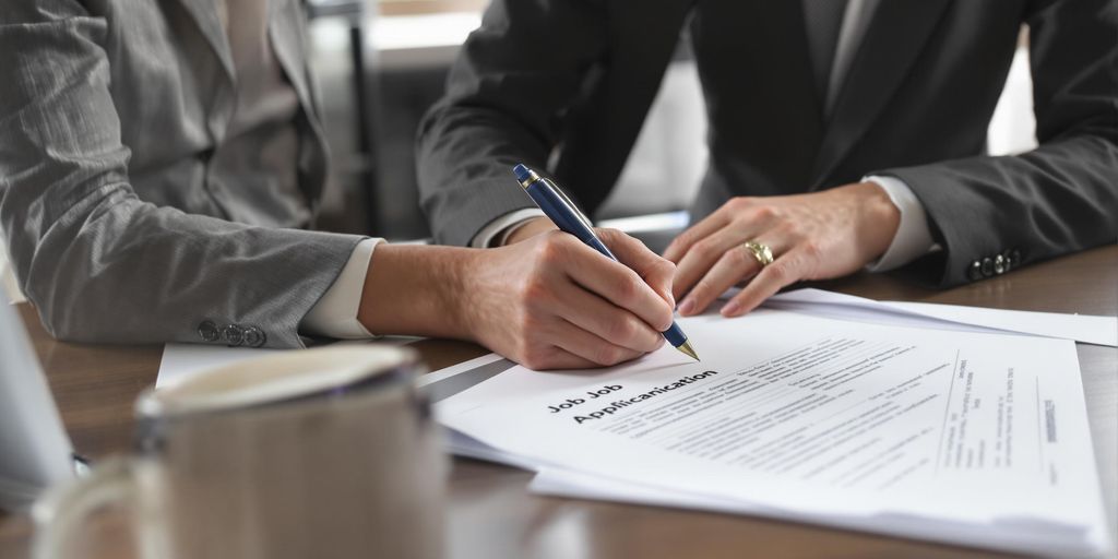 Person writing a cover letter at tidy office desk