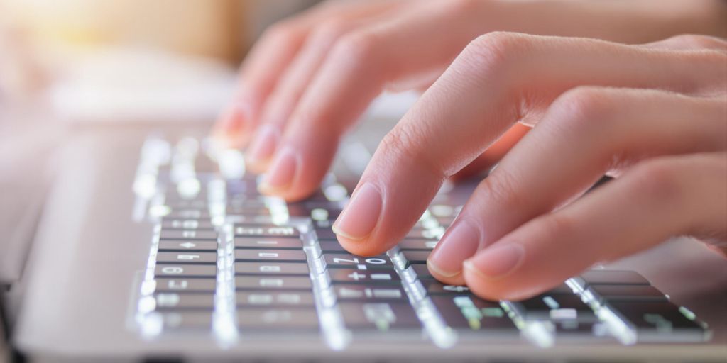 Person typing on a computer keyboard.