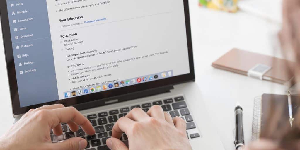 Open laptop, resume on screen, person typing.