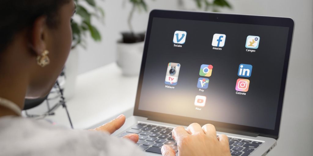 Person using laptop with social media icons.