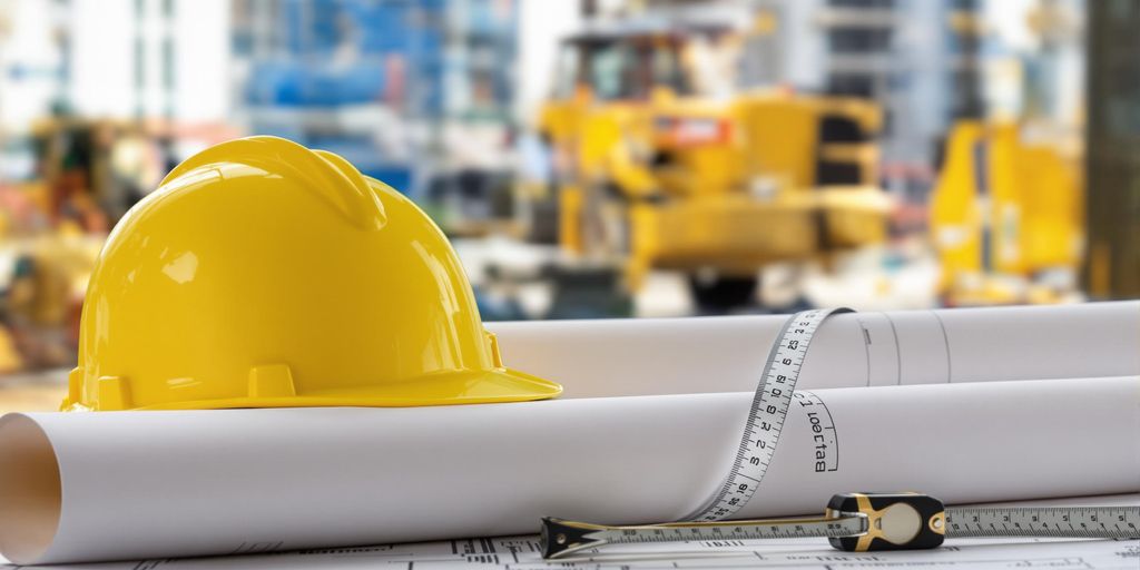 Hard hat, blueprints, and tape measure on a construction site.