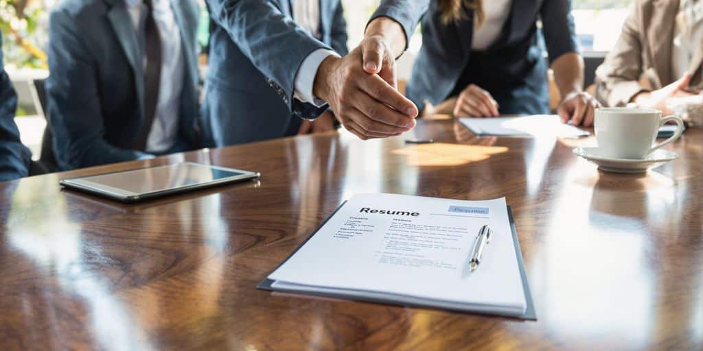 People shake hands over a resume.