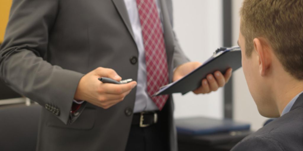 Person coaching another person with a clipboard.