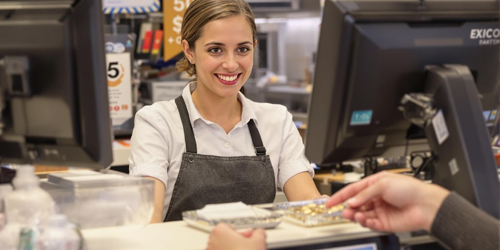 Cash register, coins, smiling cashier, customer.