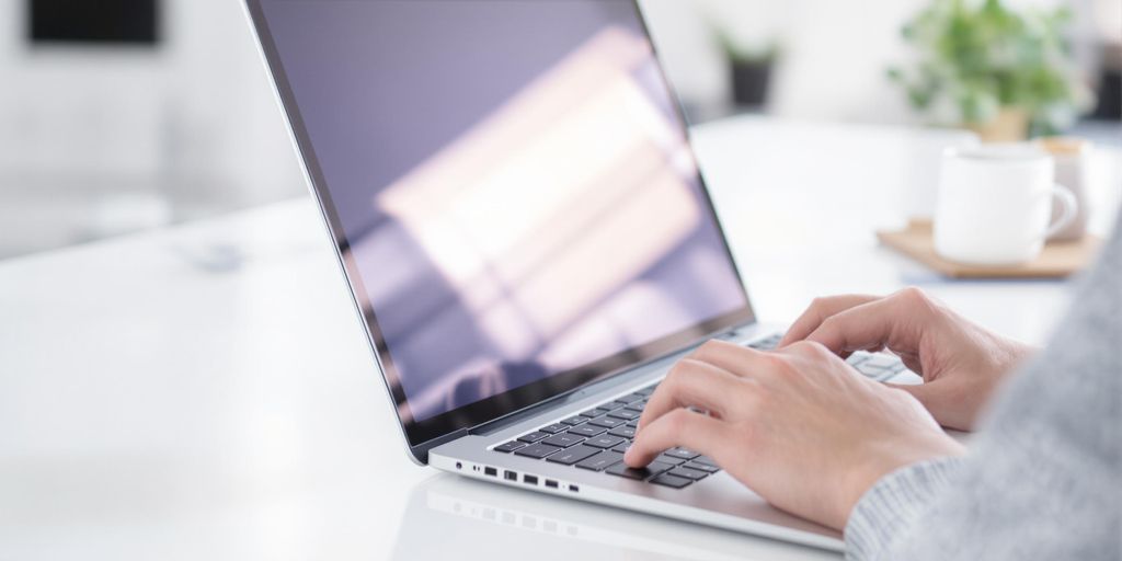 Laptop with a person typing on its keyboard.