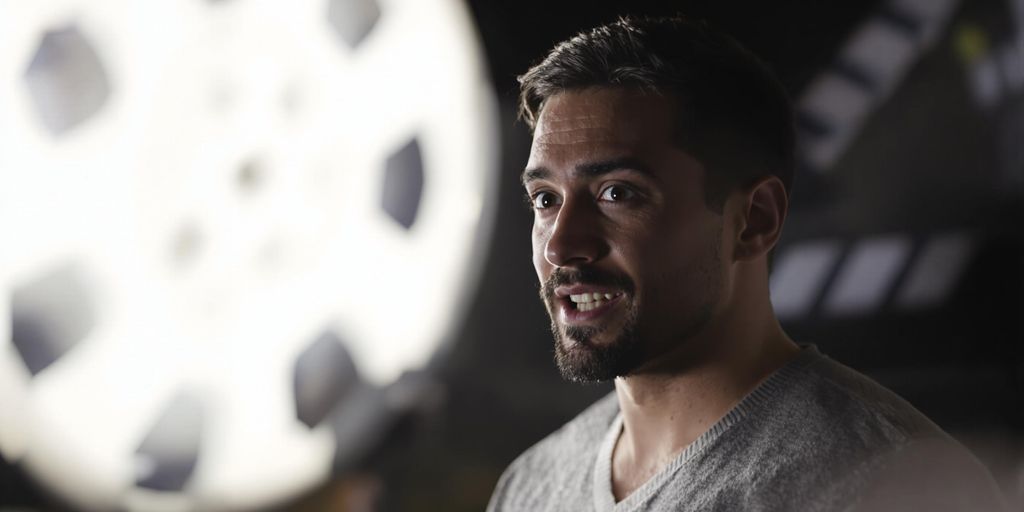 Person in spotlight, acting, with classic cinema elements.